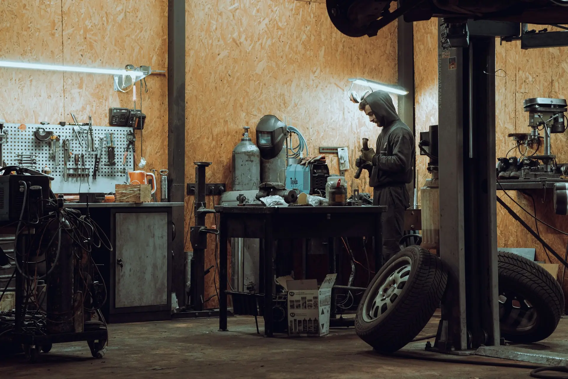 A mechanic working under a car on a lift in a repair shop