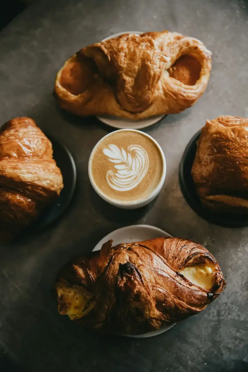 A cup of coffee surrounded by four pastries