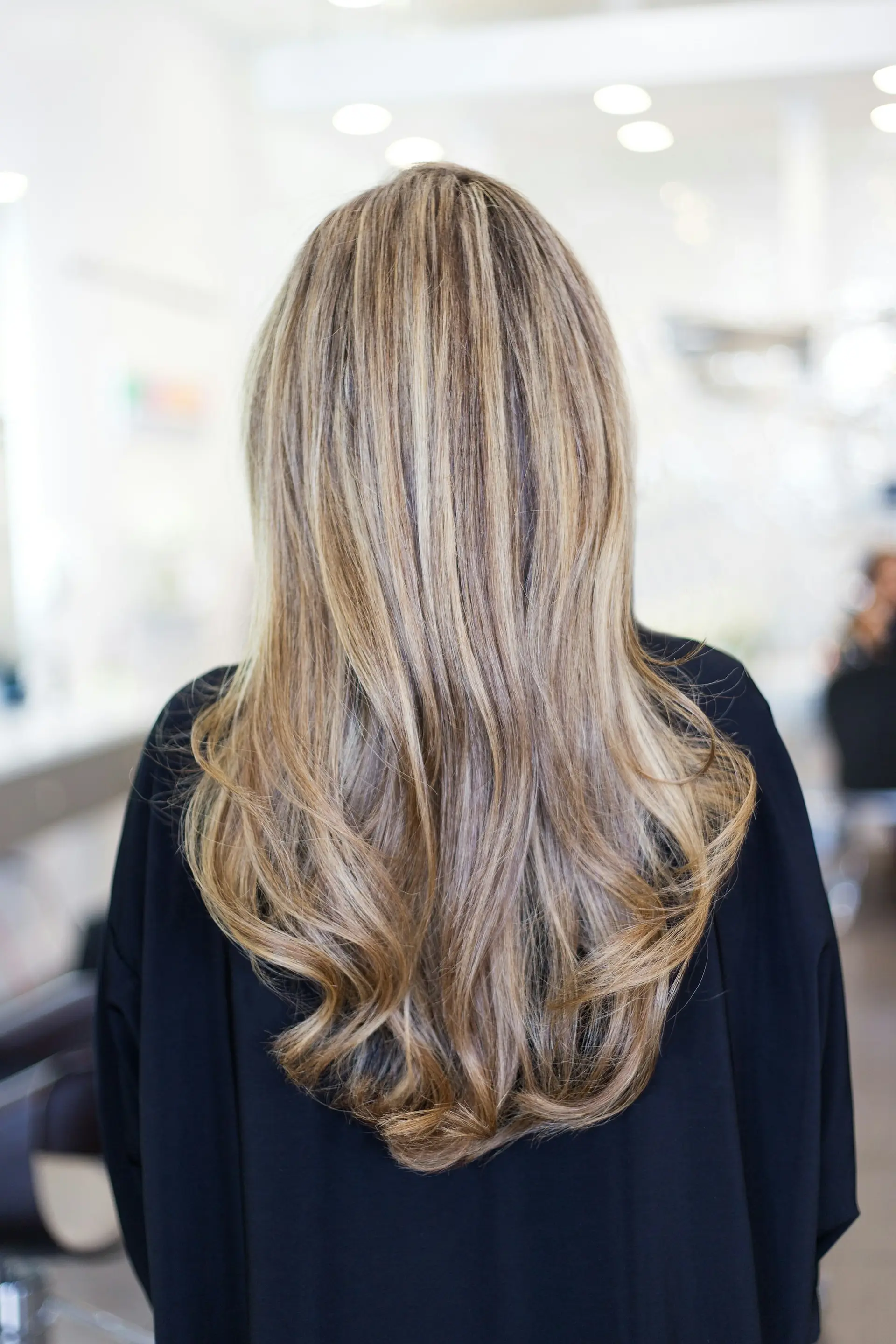 Back view of a woman with long, glossy wavy brown hair