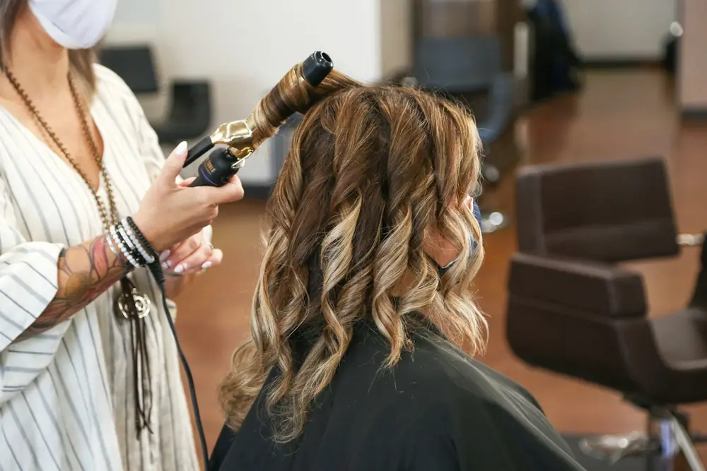 A stylist curling a client's hair with a curling iron