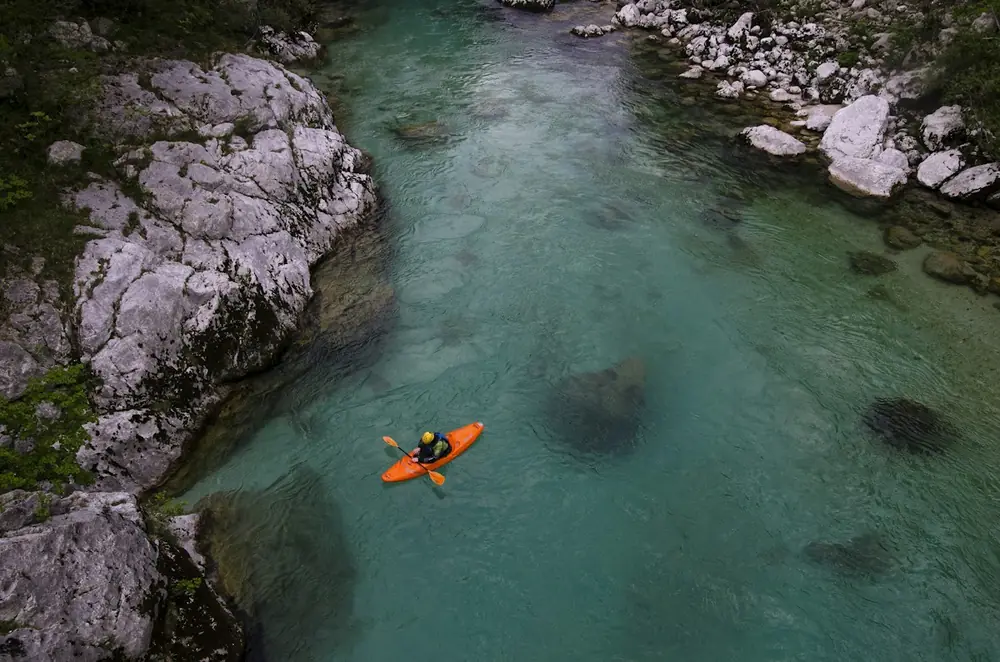 Kayaker paddling calm water below mountains
